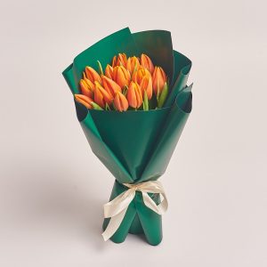 Vibrant bouquet of orange tulips wrapped in green paper, flowers theme